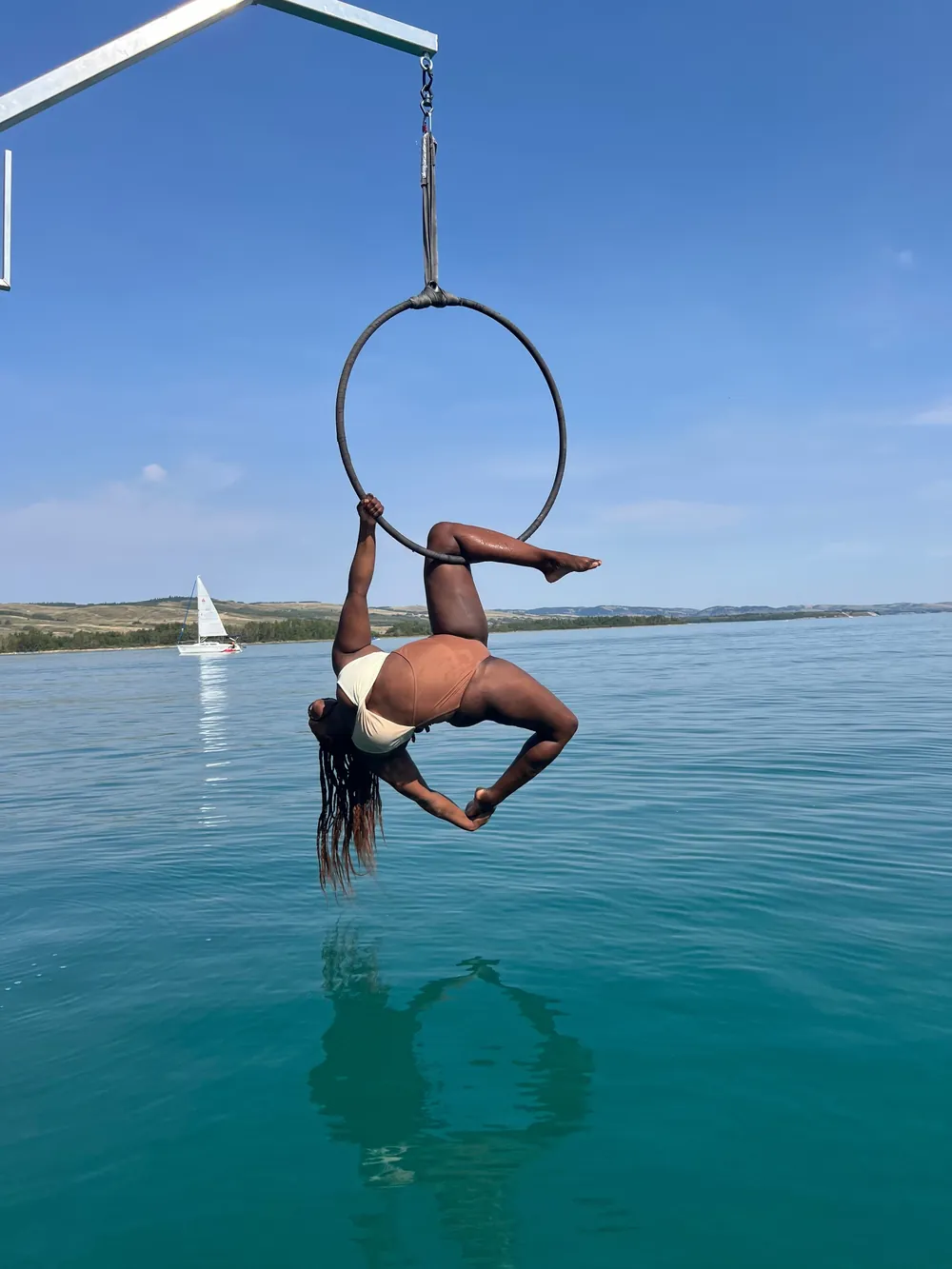 An aerialist inverted in the hoop above open water