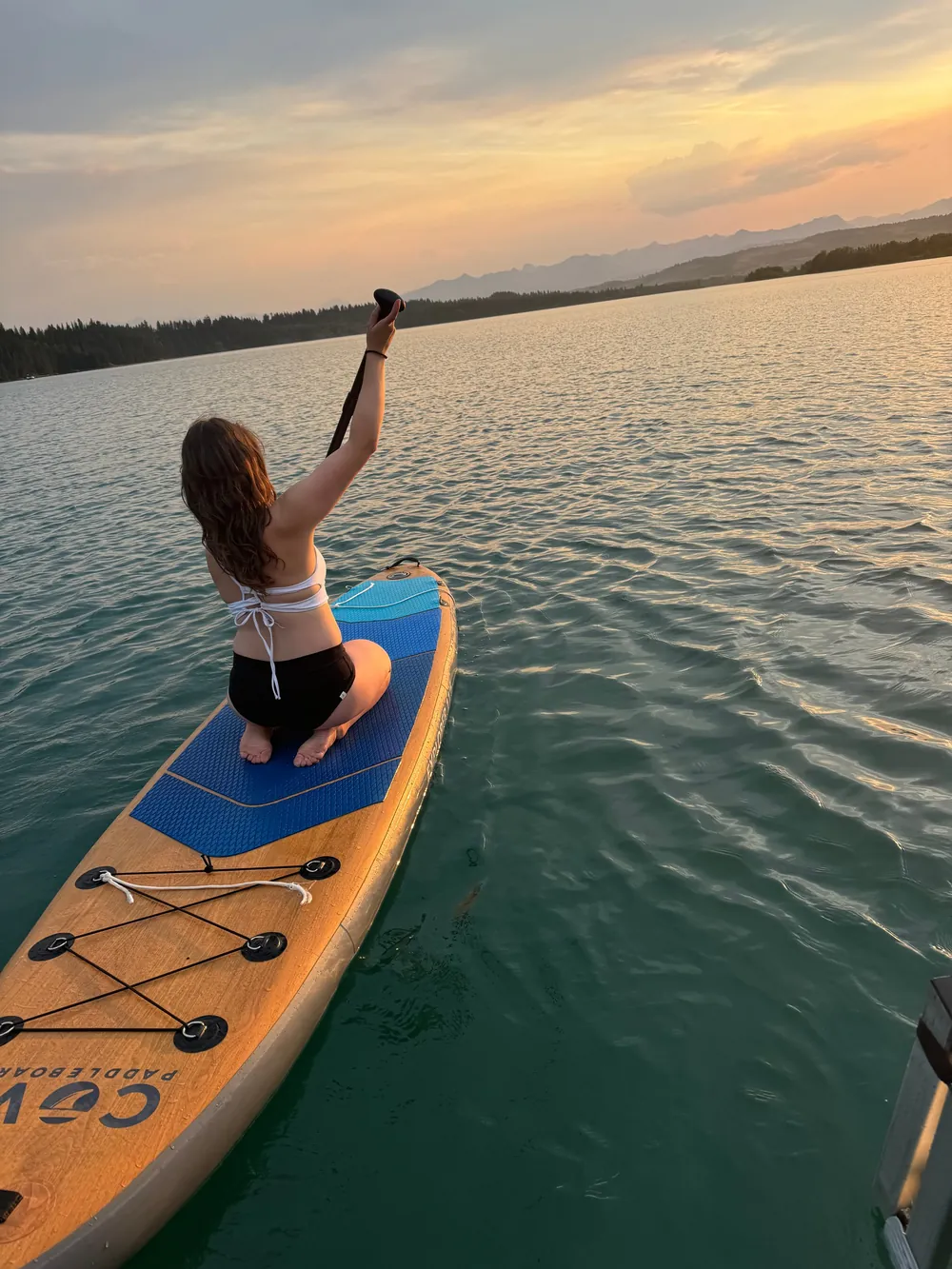 A guest paddleboarding on Ghost Lake at sunset